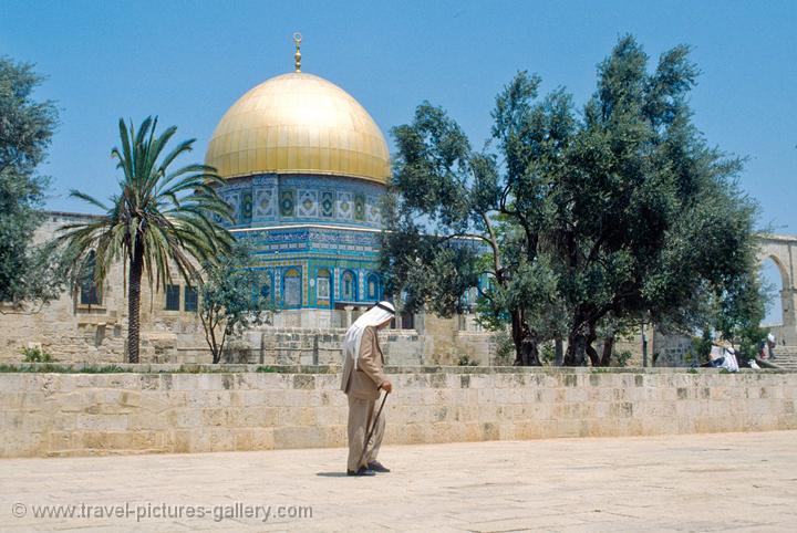an Arab man passes before the Dome of the Rock