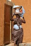 woman carrying pots on her head, toddler on the back