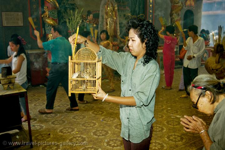 a woman releasing birds at a Cholon temple