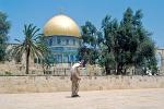 an Arab man passes before the Dome of the Rock