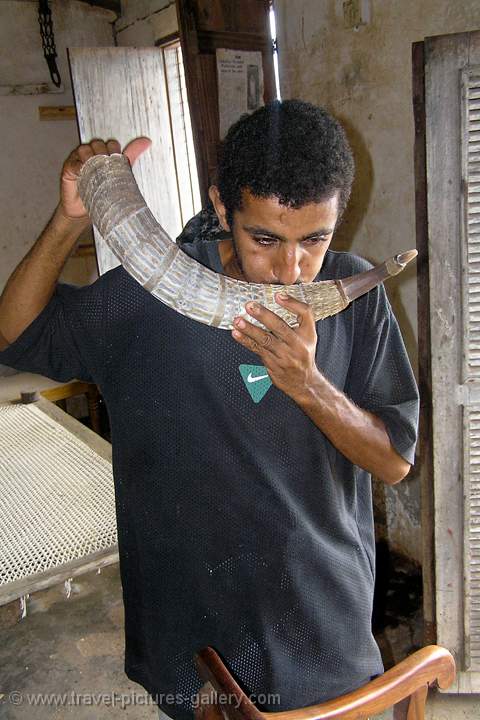 man blowing a carved horn, Lamu